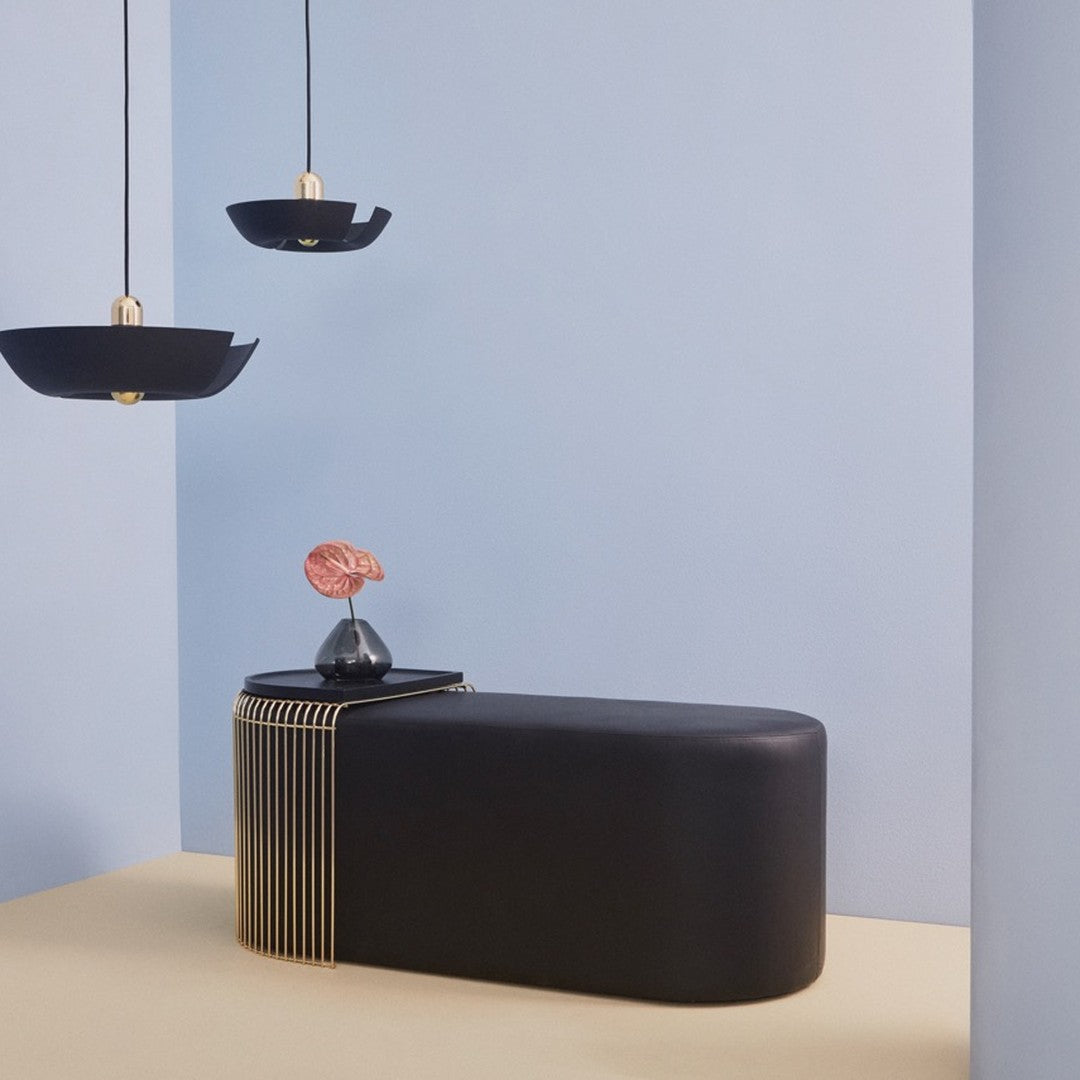 Modern black furniture with gold accents, against soft blue walls and a light beige floor.