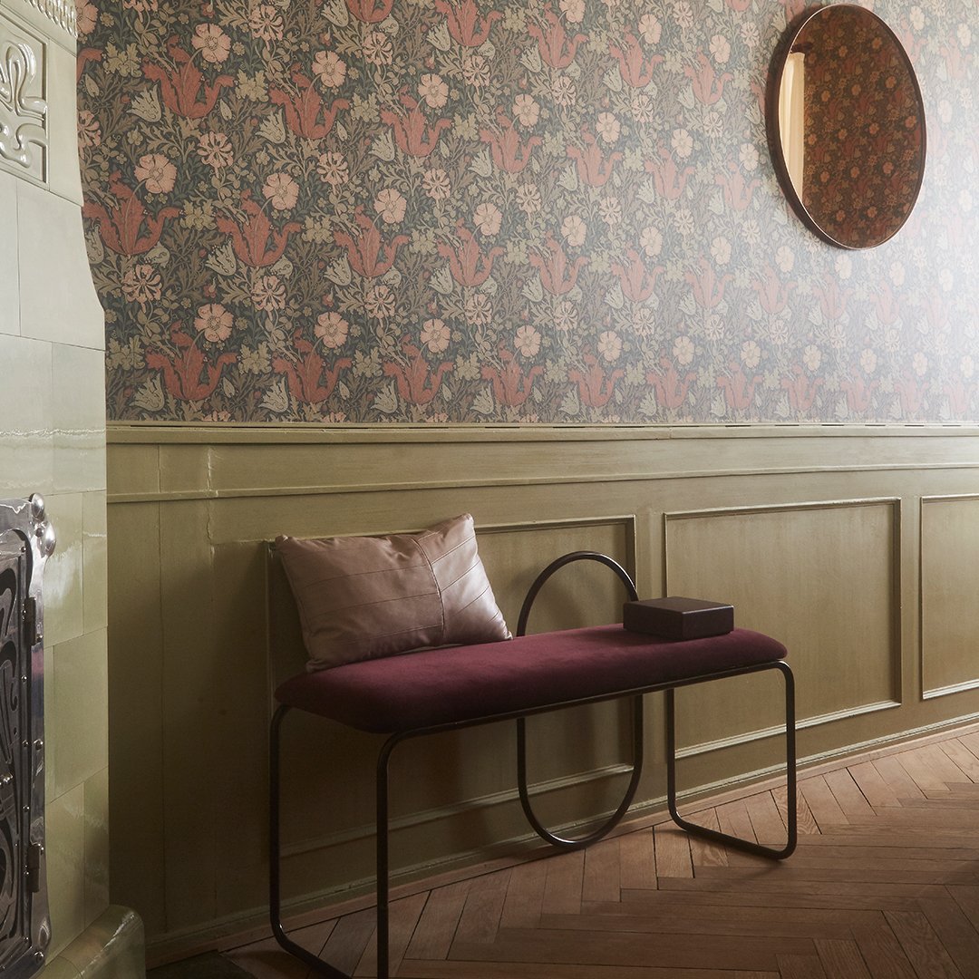 "Vintage floral wallpaper in warm tones, with a burgundy bench and neutral accents, creating a cozy interior vibe."