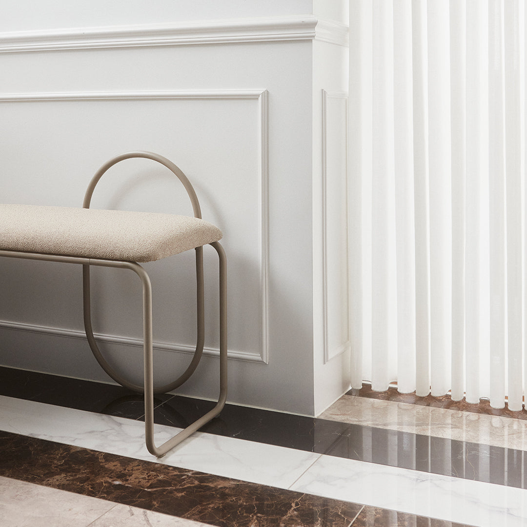 Neutral beige upholstery on a sleek metallic base against polished dark and light marble flooring. Elegant modern style.