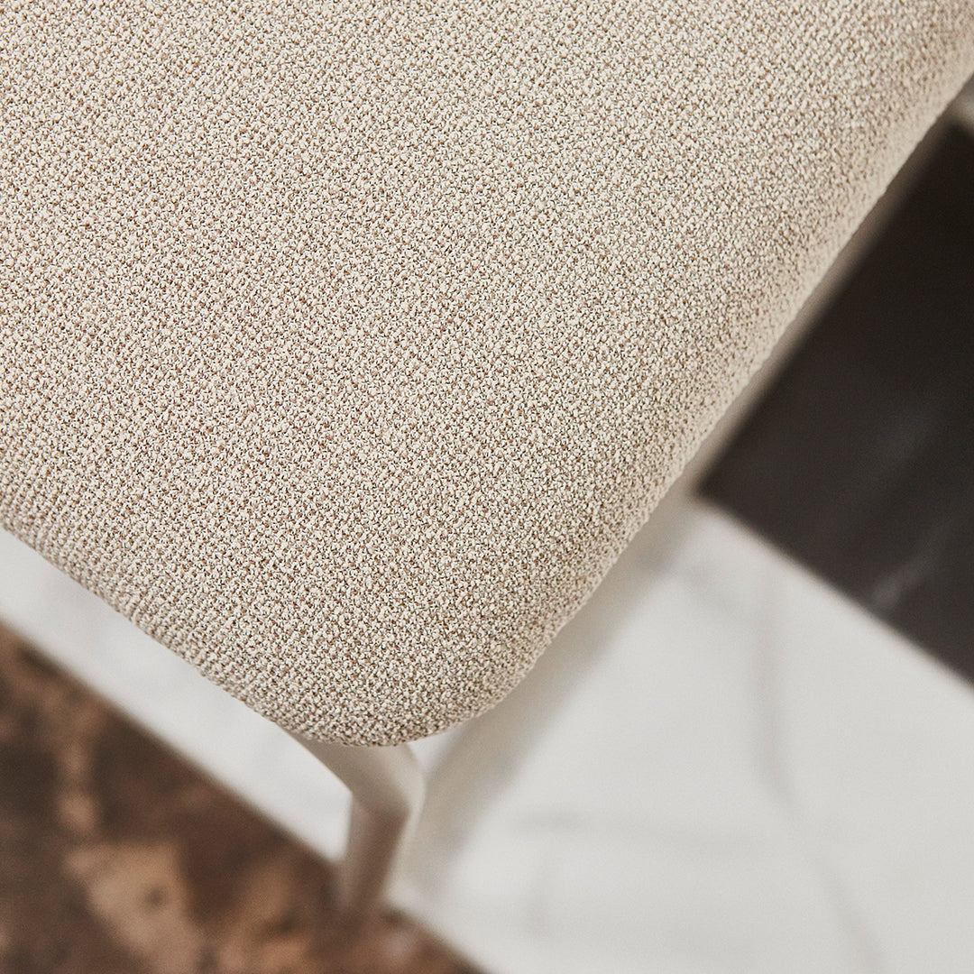 Beige textured upholstery with a subtle woven pattern on a modern chair seat.