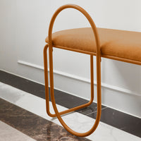 Orange upholstered bench with a sleek, circular metal frame on a marble-patterned floor.