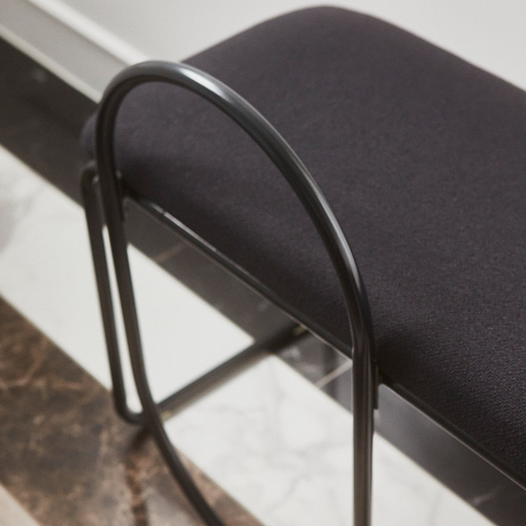 Black upholstered bench with a sleek black metal frame, featuring minimalist design and smooth textures.