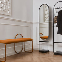 Stylish orange bench and sleek black mirror in a modern, minimalistic interior with warm wooden flooring.