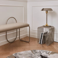 Beige bench, gold accents, wire side table, and a gray patterned rug in a modern interior setting.
