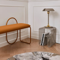 "Modern orange bench with curved legs, accompanied by a geometric metal side table and abstract patterned rug."