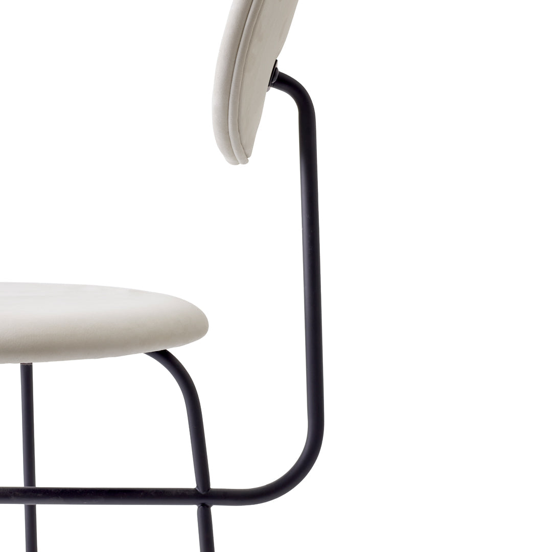 Light beige chair with a minimalist design, featuring a sleek black metal frame.
