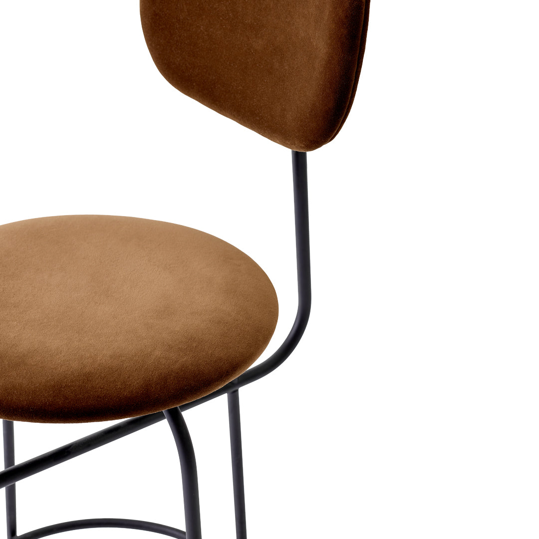 Brown velvet upholstered chair with a smooth texture and minimalist black metal frame. Ideal for modern decor.