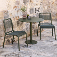 Green outdoor dining set featuring textured chairs and a smooth round table, against a rustic stone backdrop.