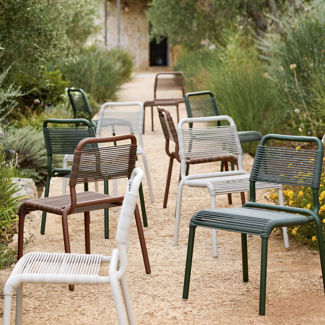 Colorful outdoor chairs in green, brown, white, and gray with woven patterns, set along a scenic pathway.