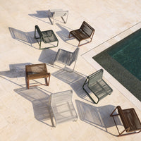 Assorted outdoor chairs in shades of gray, brown, and green, featuring a modern slatted design, arranged by a pool.