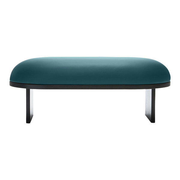 Teal velvet ottoman with a smooth, rounded surface and sleek black legs, showcasing a modern minimalist design.