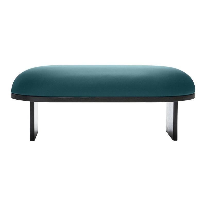 Teal velvet ottoman with a smooth, rounded surface and sleek black legs, showcasing a modern minimalist design.