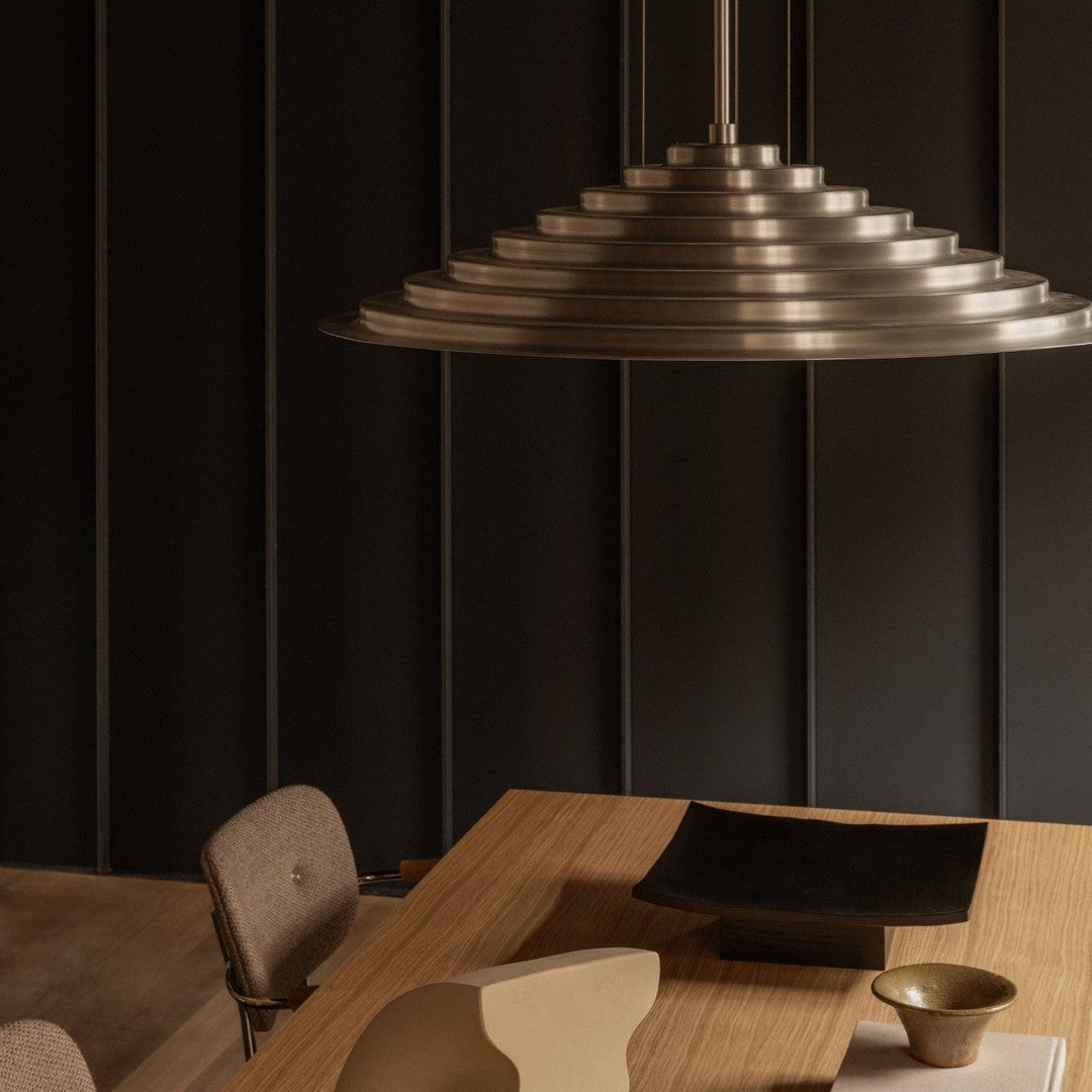 Stylish metal pendant light in gradient silver, complemented by earthy wood tones and neutral shades. Modern, minimalist design.