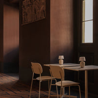 Modern dining area featuring earthy tones, neutral chairs, and geometric patterns on the floor. Elegant ambience.