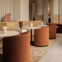 Contemporary cafe setting with rust-colored chairs, cream tables, and beige tones in a warm, inviting atmosphere.