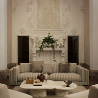 Beige and cream striped sofa with neutral throw pillows in a stylish living room setting. Elegant, modern design.