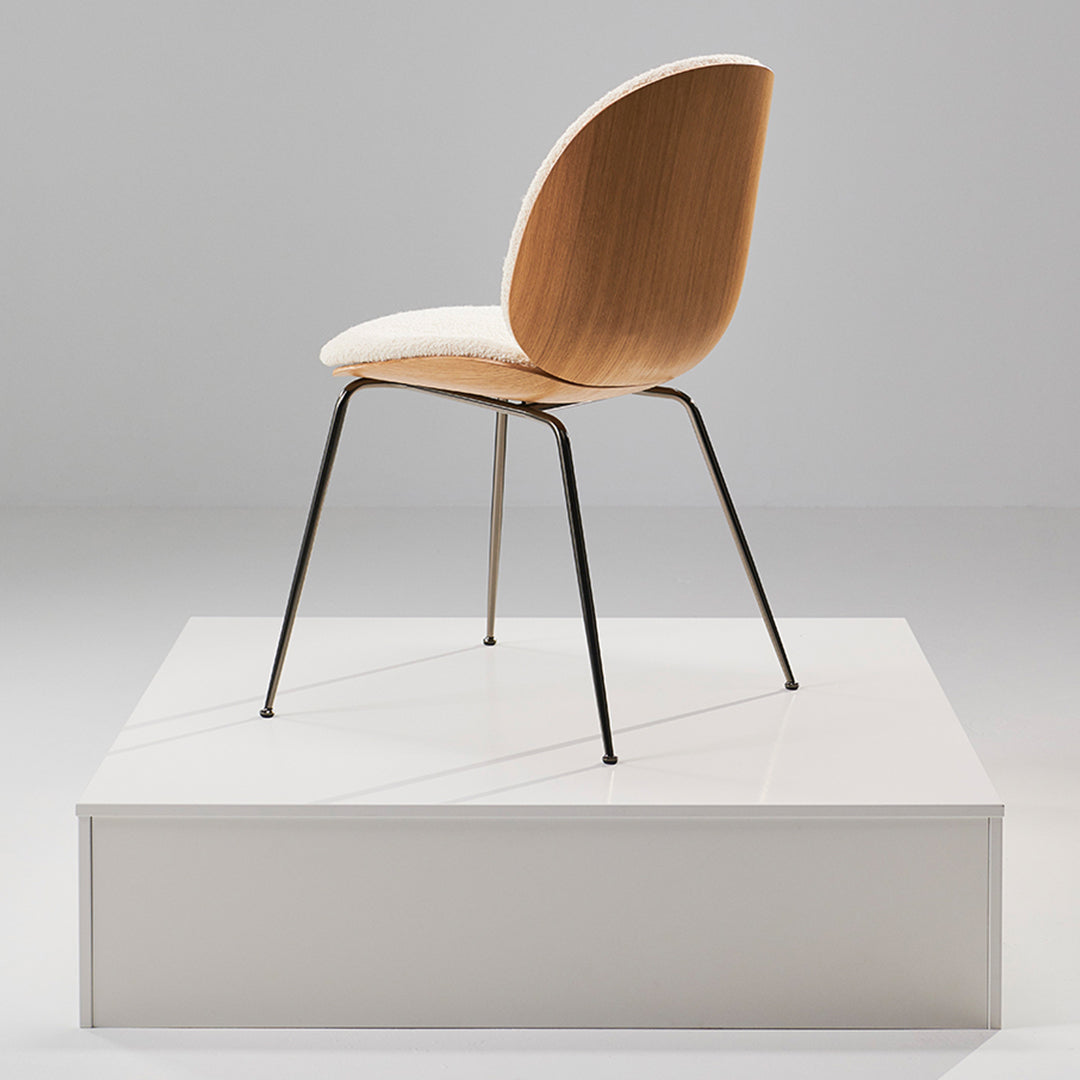 Modern wooden chair with a light beige seat and sleek black metal legs, displayed on a minimalistic white platform.