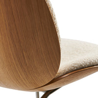 Wooden chair back with warm brown tones, featuring a soft, cream textured seat for a stylish contrast.