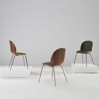 Three stylish chairs in brown, green, and black hues with smooth, modern designs displayed on white platforms.