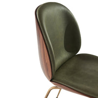 Olive green leather chair with a smooth, curvy design and walnut wood accents. Stylish and modern pattern.
