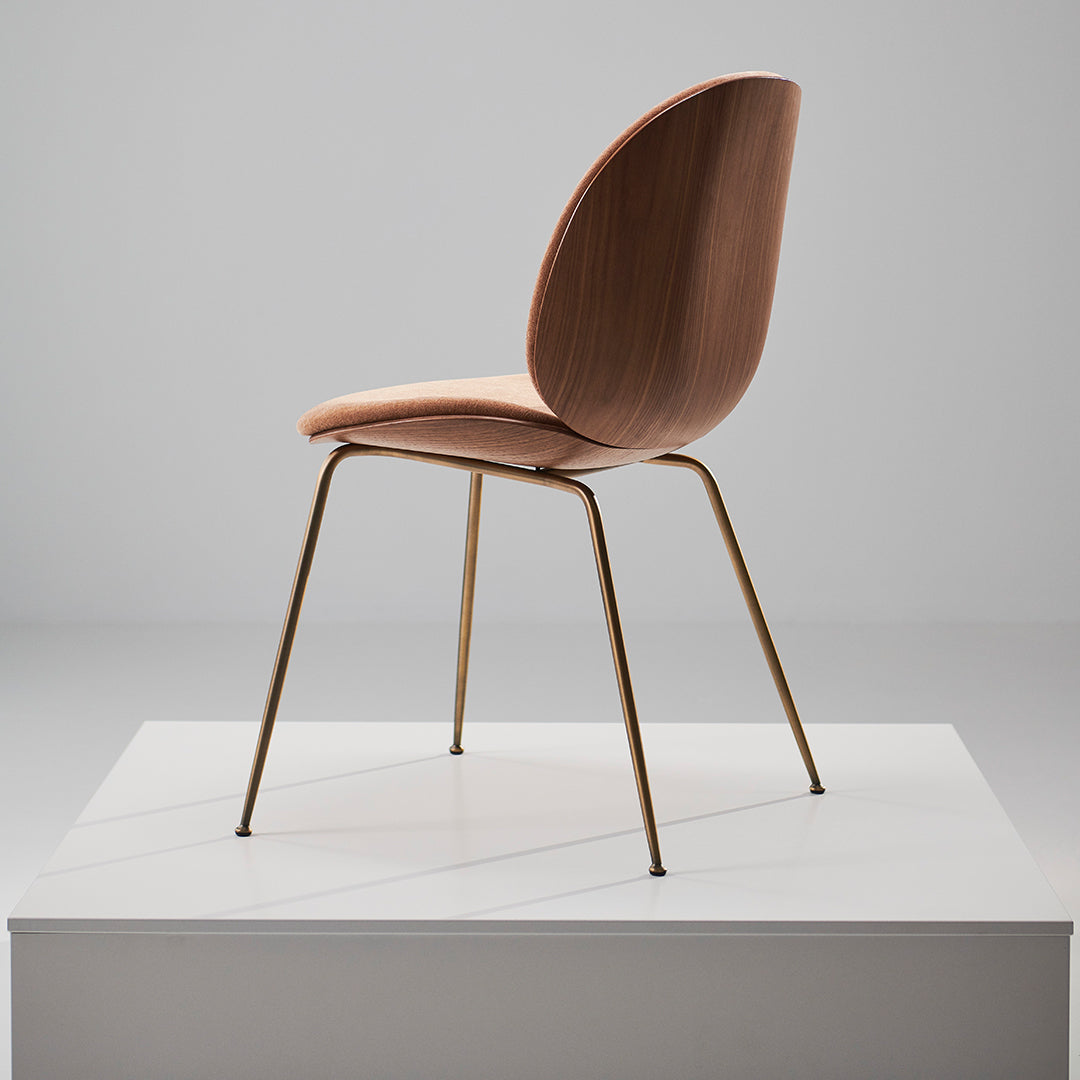 Elegant pink chair with smooth curves, showcasing a minimalist design and a sleek gold base.