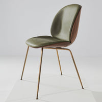 Olive green and brown patterned chair with sleek metal legs, modern design on a light background.