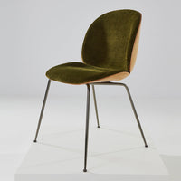 Olive green velvet chair with a wooden backrest and sleek black metal legs, minimalist design.