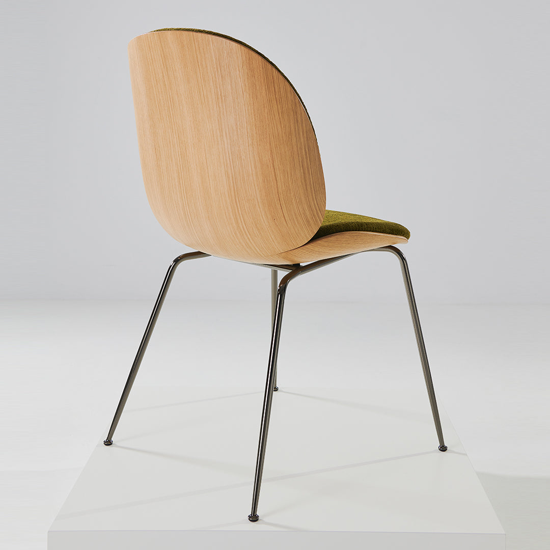 "Modern chair with a light wood finish, green upholstered seat, and sleek black metal legs on a white platform."