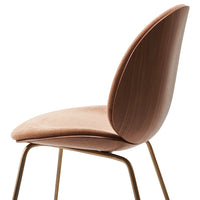 Blush pink upholstered chair with smooth curves and brass legs, featuring a minimalist modern design.