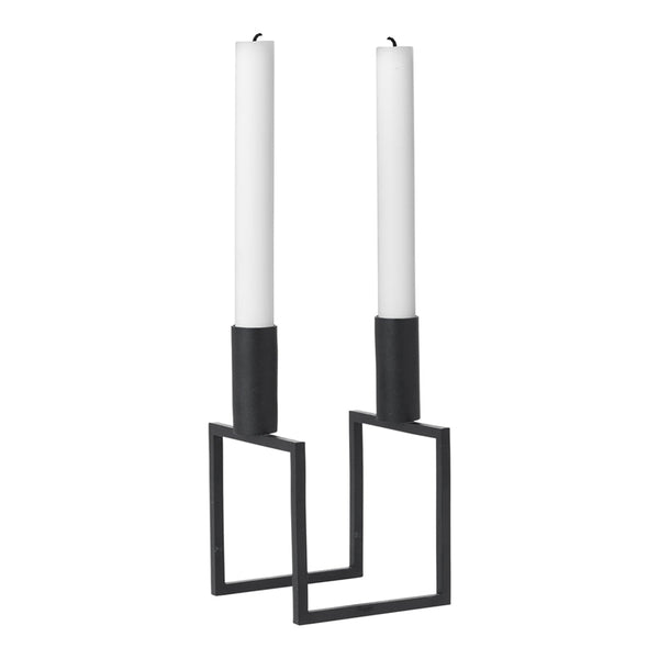 Black metal candle holders with white candles, featuring a modern geometric design.