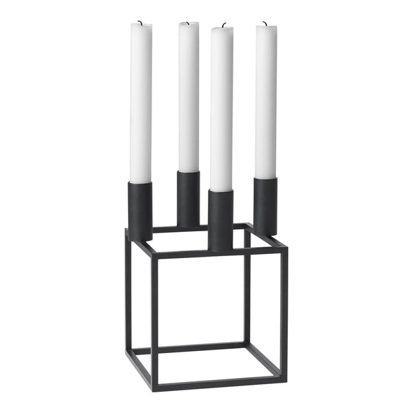 Modern black metal candle holder with four tall white candles, featuring a sleek geometric design.