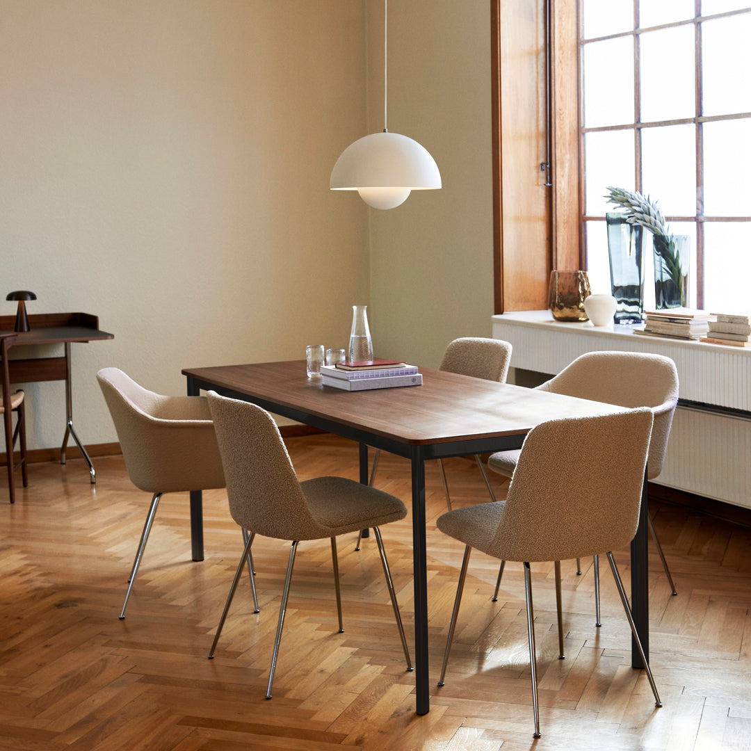 Modern dining table with a walnut finish, complemented by beige upholstered chairs and warm, neutral room tones.