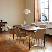 Modern dining table with a walnut finish, complemented by beige upholstered chairs and warm, neutral room tones.