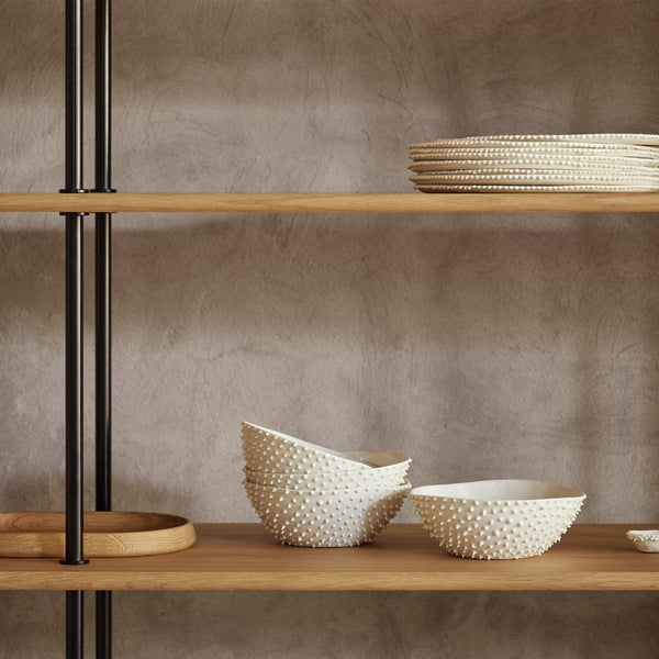 White textured bowls on wooden shelves with a minimalist design against a soft gray wall. Perfect for modern decor.