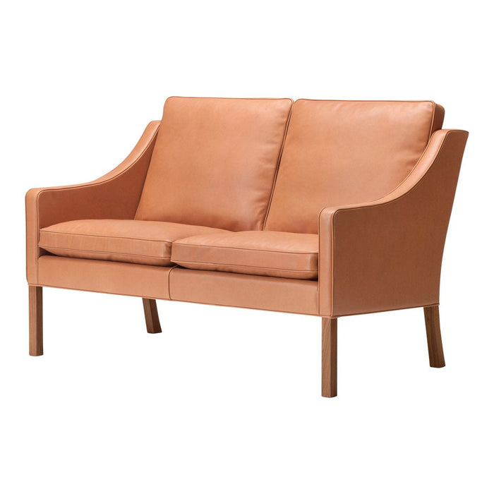 Tan leather loveseat with smooth texture and minimalistic design, featuring solid wood legs. Perfect for modern decor.