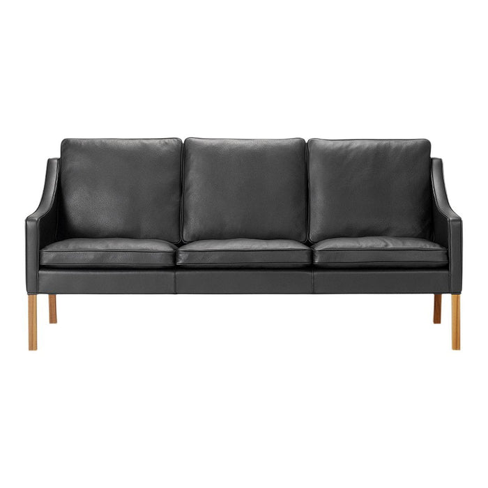 Black leather sofa with smooth surface, featuring three cushions and wooden legs for a modern touch.