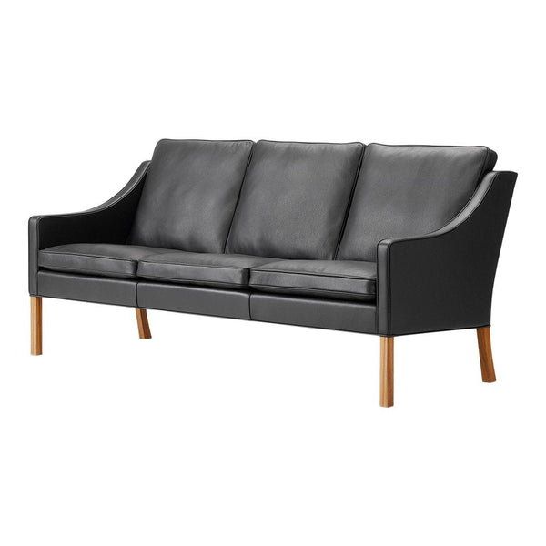 "Modern black leather sofa with smooth texture and wooden legs, showcasing sleek, minimalist design."
