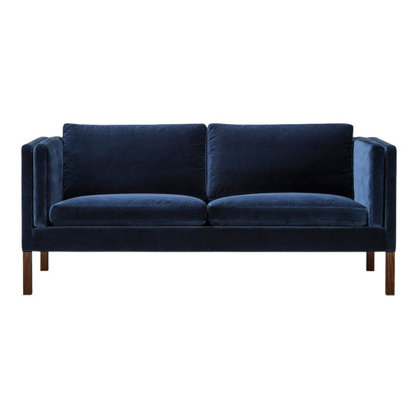 Navy blue velvet sofa with a sleek, modern design and plush cushions, featuring understated wooden legs.