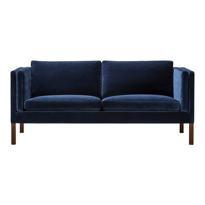 Navy blue velvet sofa with a sleek, modern design and plush cushions, featuring understated wooden legs.