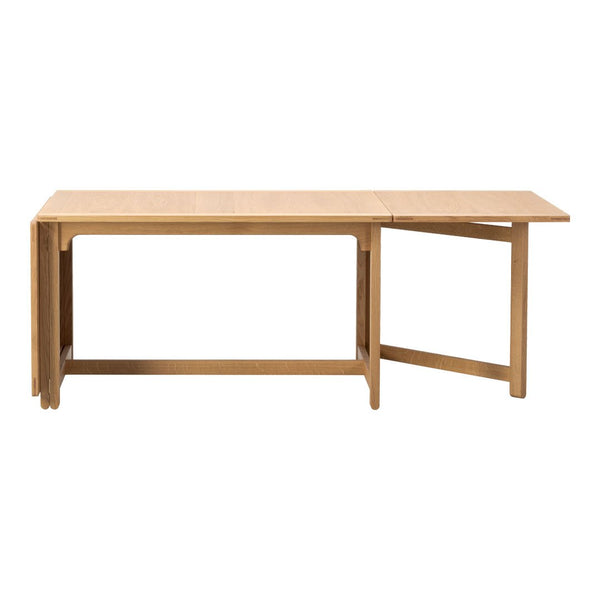Light-colored wooden table with a minimalistic design and smooth surface, featuring natural wood grain patterns.