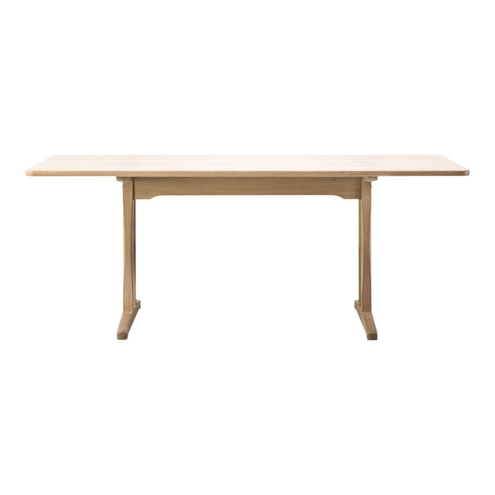 Light natural wood dining table with a smooth finish and simple, clean lines for a modern aesthetic.