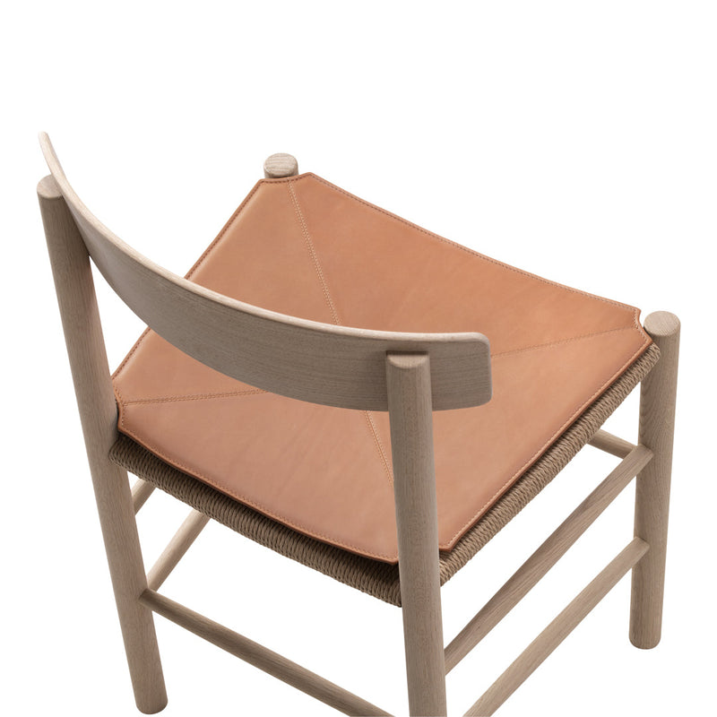 Light wood chair with a tan leather seat and natural rope detailing, featuring minimalist design and clean lines.