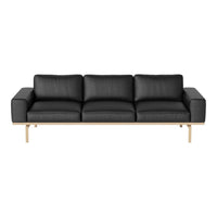 Modern black leather sofa with sleek lines and minimalistic design, featuring light wood legs for contrast.