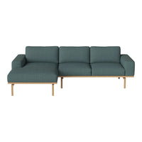 Teal upholstered sectional sofa with a modern design and light wood accents, featuring a smooth, textured fabric.