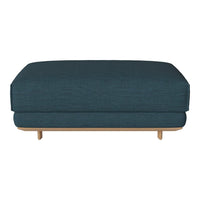 Teal upholstered ottoman with a smooth texture and minimalist design, featuring a natural wood base.