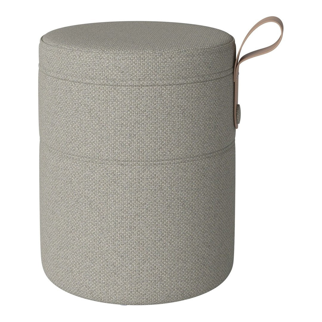 Light gray cylindrical storage ottoman with a textured pattern and a leather handle. Modern and minimalist design.