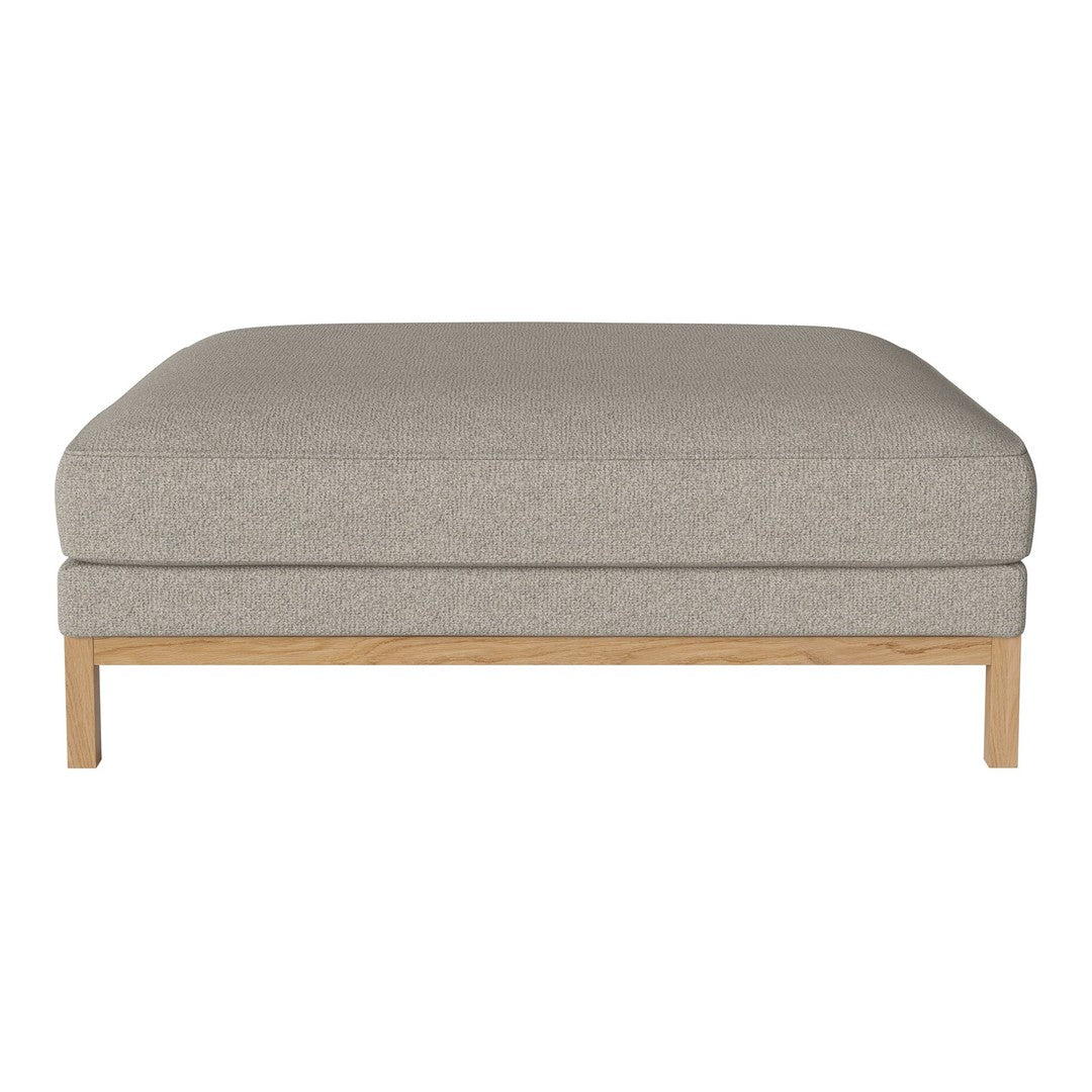 Light gray upholstered ottoman with a minimalist design and natural wood base. Soft, textured fabric complements neutral decor.