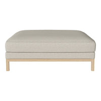 Light beige ottoman with a textured fabric and simple wooden base. Modern, minimalist style for versatile decor.