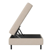 Beige upholstered ottoman with lift-top design and sleek black base, perfect for modern decor.