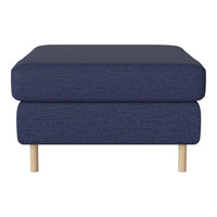 Navy blue upholstered ottoman with textured fabric and light wooden legs. Stylish and modern home decor accent.